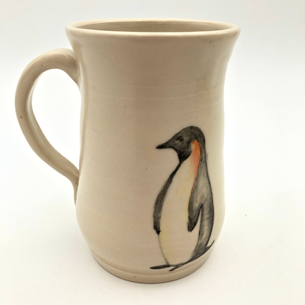 White pottery mug with a hand painted penguin on the front